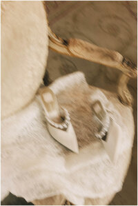 Details of a bride’s shoes with pearls on a vintage chair