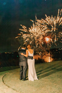 bride and groom look at the large firework display as a surprise to their wedding guests.