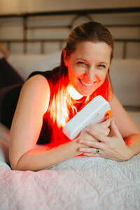 Woman lying on a bed using a red light device