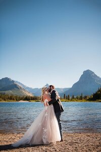 A happy couple kiss each other at sunset on their wedding day in Glacier National Park in Montana.