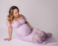 Pregnant woman wearing purple dress in a Cleveland photo studio