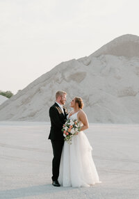 A bride and groom stand in front of a gravel pit near their wedding at Port 393 in Holland