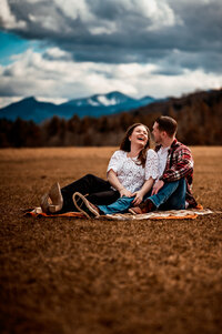 A couple laughs together in a field in the adirondack mountains near keene valley