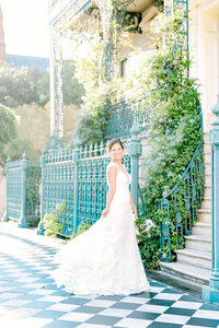 Bride twirls her dress for photographer atop a charming checkerboard sidewalk in front of the historic John Rutledge Inn on a bright and sunny evening downtown Charleston, SC. Captured by Kara Blakeman Photography, specializing in romantic, joy-filled wedding and portrait photography in the lowcountry.