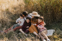 Gorgeous family seated on a cream blanket in a field of tall golden grass