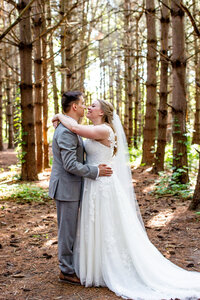 Elopement couple standing in forest of trees taken by Kalena Photography.