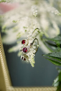 Ruby and diamond drop earrings with gold settings displayed on a mirror tray worn by the bride at her luxury wedding.