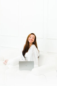 Coastical Designs, a luxury branding and custom website design expert, standing next to windows with an iPad, showcasing her professional approach to creative branding solutions and custom web design services.