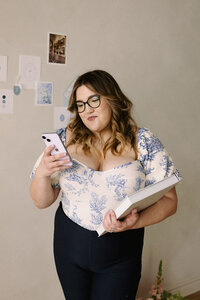 Wedding planner, Zelie & Co., looking at her phone while holding a planner 
