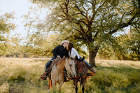 couple kissing while horseback at their engagement session in texas
