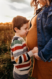 young boy kissing his mother's pregnant belly.  photo taken by phialdelphia maternity photographer, Kristi