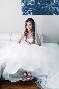 Bride sitting on the couch with her gown all spread out around her. 
