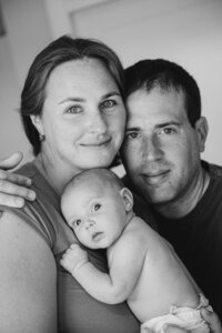 new parents with newborn in black and white looking straight into camera