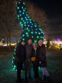Jordins family standing in front of a lit up Christmas tree.