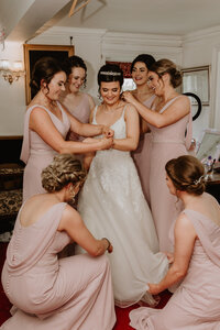 bridesmaids help bride dress