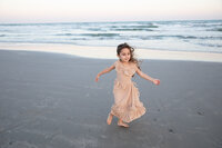 A little girl running on the beach at sunset captured by an Austin wedding photographer.