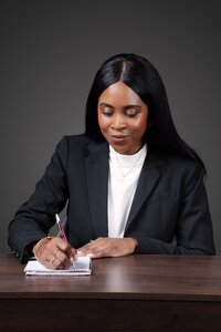 Jessica wearing a white blazer, smiling as she writes in her planner