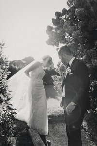 Candid black and white photo of bride and groom walking together in the garden during their Portland Maine wedding.