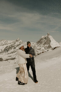Couple popping champagne during winter elopement in Zermatt.
