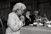 Cupcake with a candle being celebrated for a grandmother’s 90th birthday during a Colorado wedding reception.
