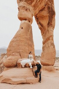 Eloping couple standing beneath the towering rock formations of Double Arch in Arches National Park