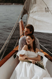bride and groom snuggle on sunset sailboat ride