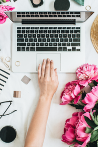 A womans hand reaches for her computer to use honeybook crm