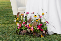 pink and yellow flowers on green grass next to white tablecloth