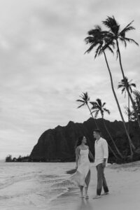 Een kus op een strand van O'ahu in Hawai'i. Het koppel staat tussen de metershoge palmbomen, vastgelegd door Sharon Kastelijns Photography.