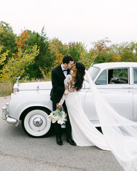 Couple kisses in front of DFW Vintage rental car during their Dallas wedding