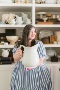 Lauren holds forward a white stoneware pitcher from her collection