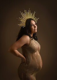 Pregnant woman wearing gold crown at a photo studio in Klamath Falls