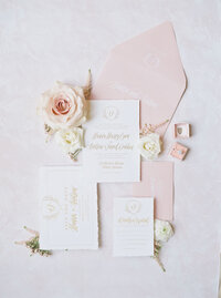 pink and white floral arrangement placed over white wedding invitiations