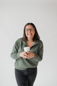 A person smiling and holding a coffee cup 