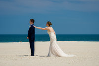 Bride tapping her groom on the shoulder during a first look on the beach at the Jersey Shore.