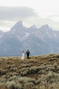photo of bride and groom walking in a field with horses taken by Intimate wedding photographer Jackson Hole