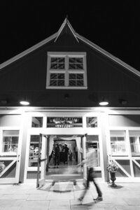 long exposer shot of guests walking in front of red barn entryway at night