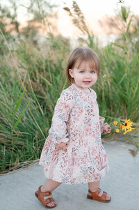 This cute girl picking flowers during a golden hour family session in Saratoga Springs, Utah