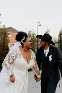 A wedding couple holding hands and smiling together