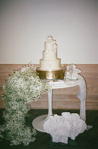 Three-tiered white wedding cake with baby’s breath floral detail, designed for a luxury wedding by The Eventful Gals.