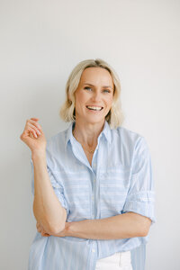Zelda Green, money and mindset educator and entrepreneur, smiling at camera looking relaxed and happy in a light blue shirt