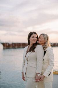 two women embracing while standing in front of water