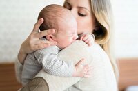 A woman holds and comforts a newborn baby.