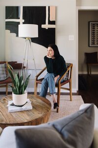 Hope Danyla sitting in a chair in a modern living room, designed by Hope Miriam Designs in DFW