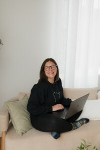 A person sitting on a couch with an open laptop 