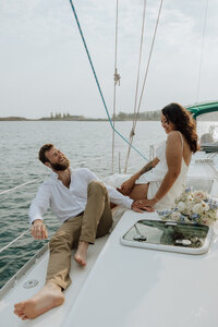 bride and groom on a sailboat on lake superior sitting and laughing together