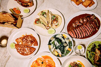 A colorful and appetizing overhead shot of assorted dishes including tacos, salad, and other vibrant plates. Captured by Mica McCook, this image showcases the diversity and richness of a well-rounded meal, perfect for sharing and enjoying with others.