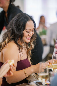 wedding guest wearing maroon smiling while eating