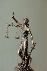 bronze lady justice statue against a light green background
