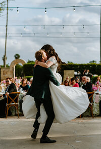 groom picking up bride while spinning with brides dress flowing in wind